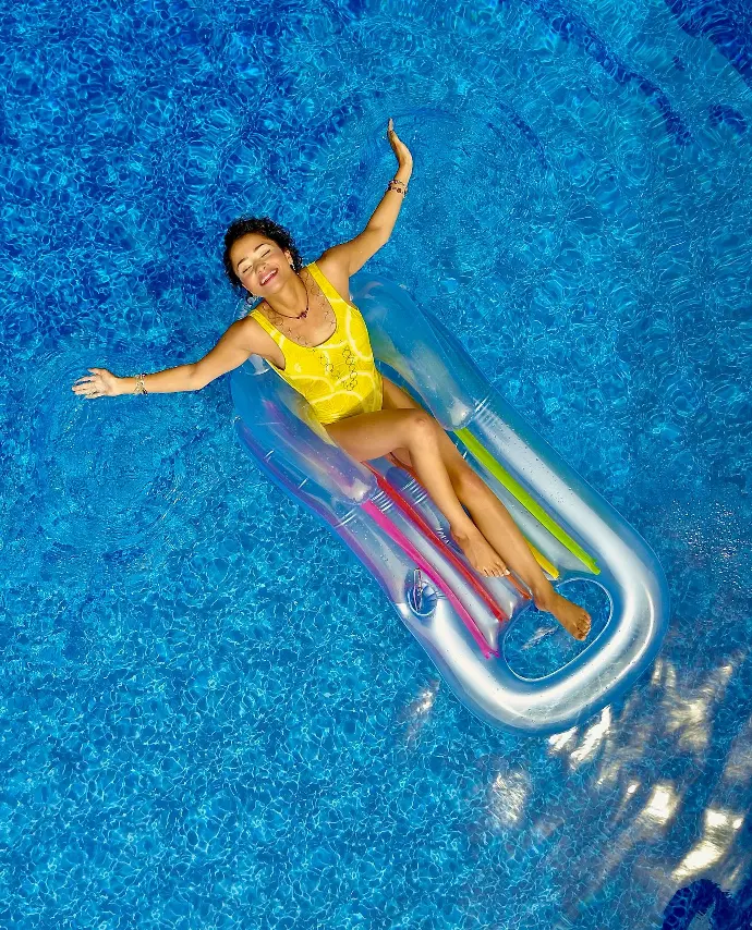 woman riding on plastic floating buoy on body of water